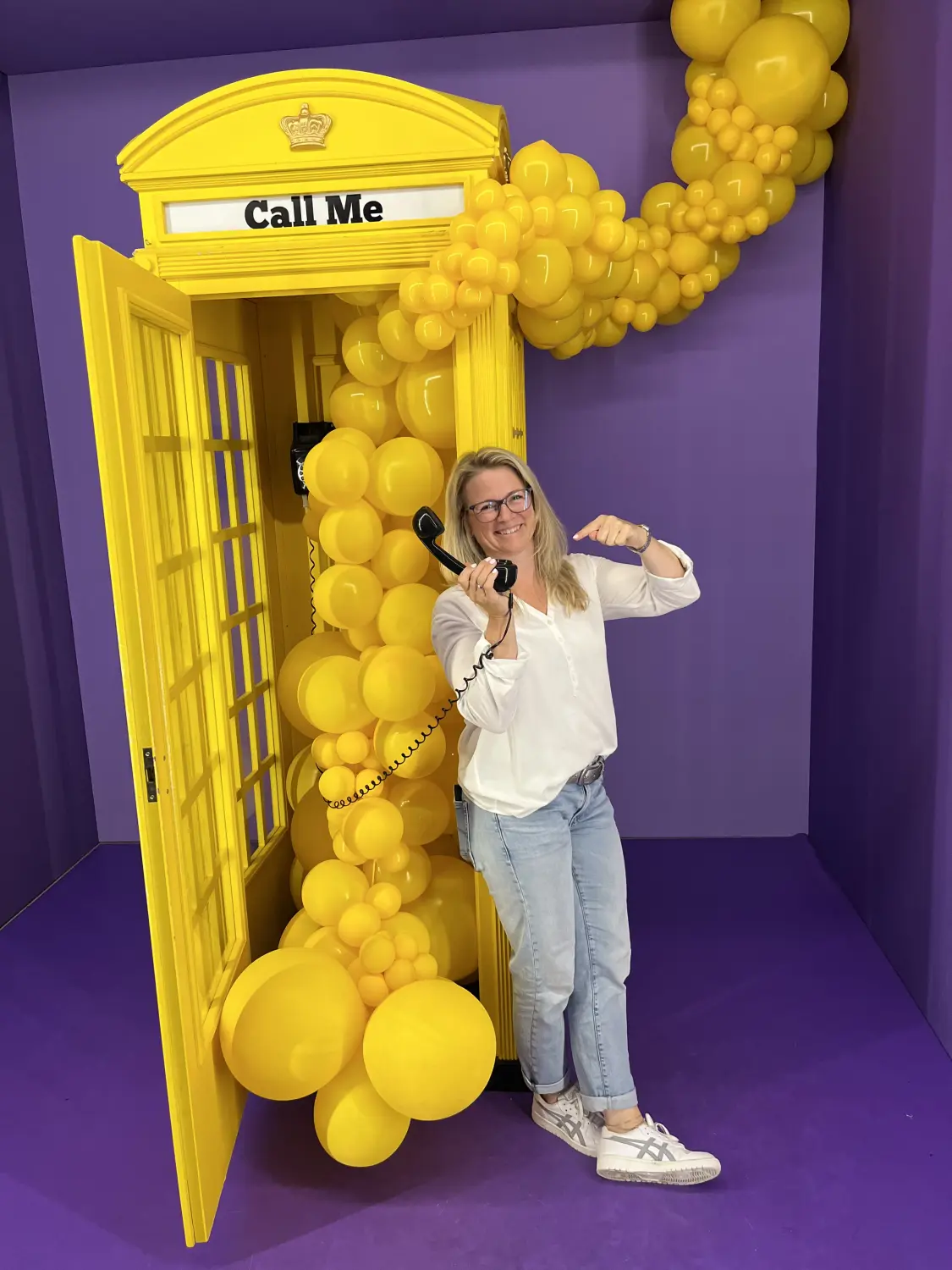 Kirsten steht an der gelben Telefonzelle und hält das Telefon 